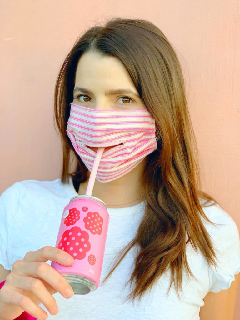 Woman sipping her drink with a face mask with a zip