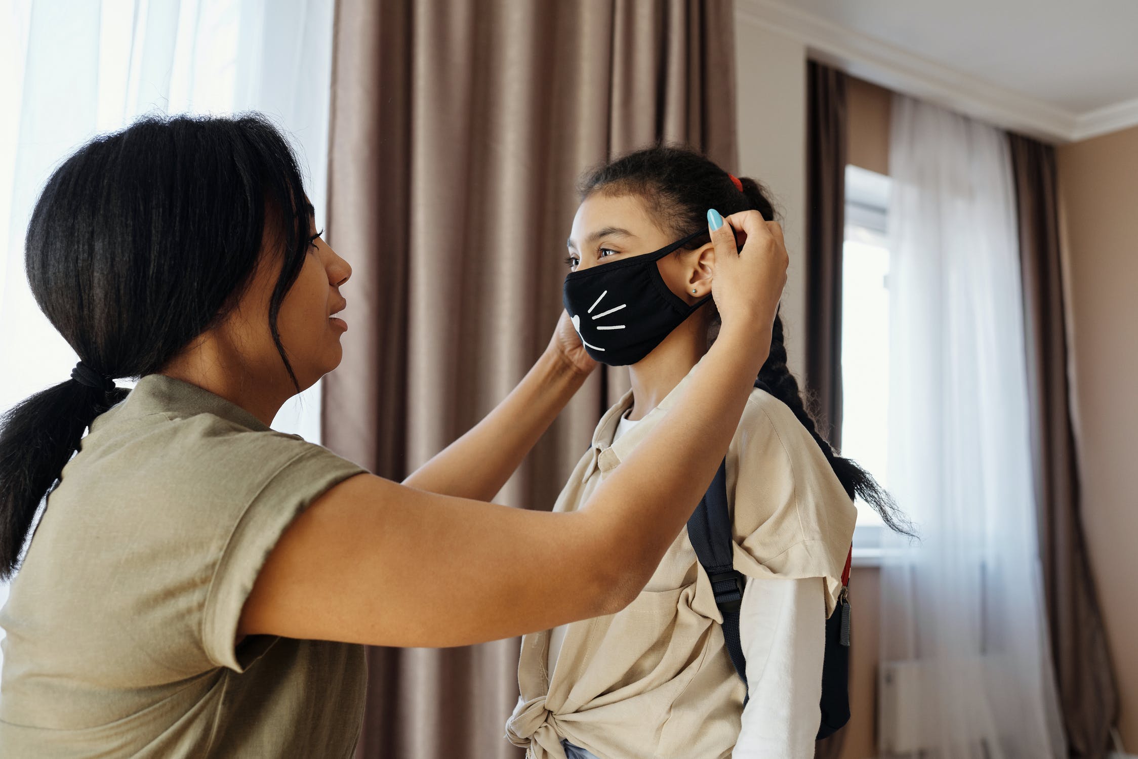 Mother putting a face mask on her kid